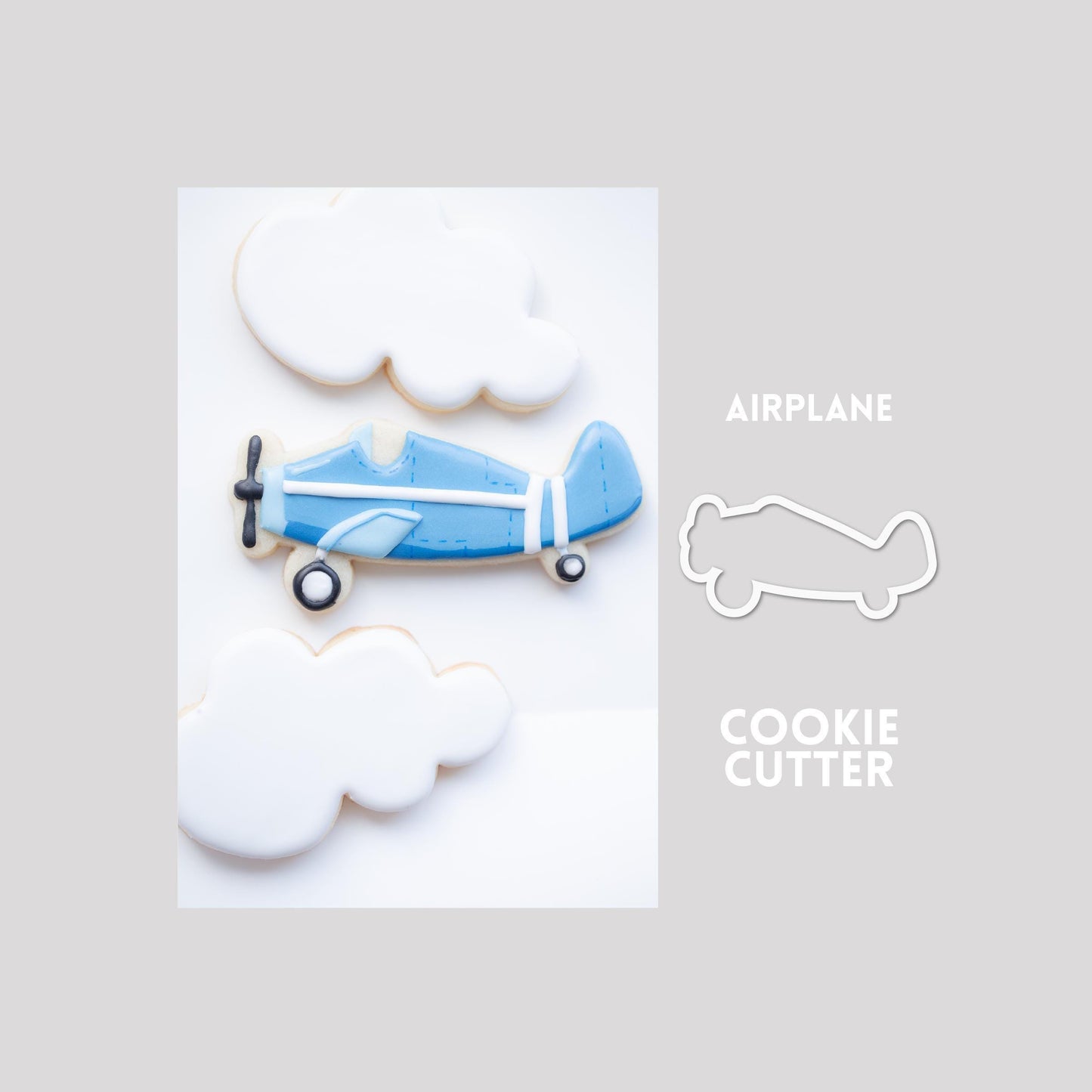 Decorated airplane sugar cookie next to a airplane cookie cutter outline on a gray background.