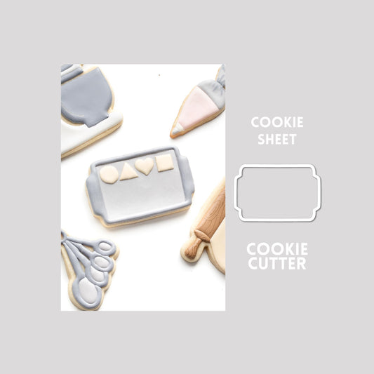 Decorated cookie sheet sugar cookie next to a cookie sheet cookie cutter outline on a gray background.