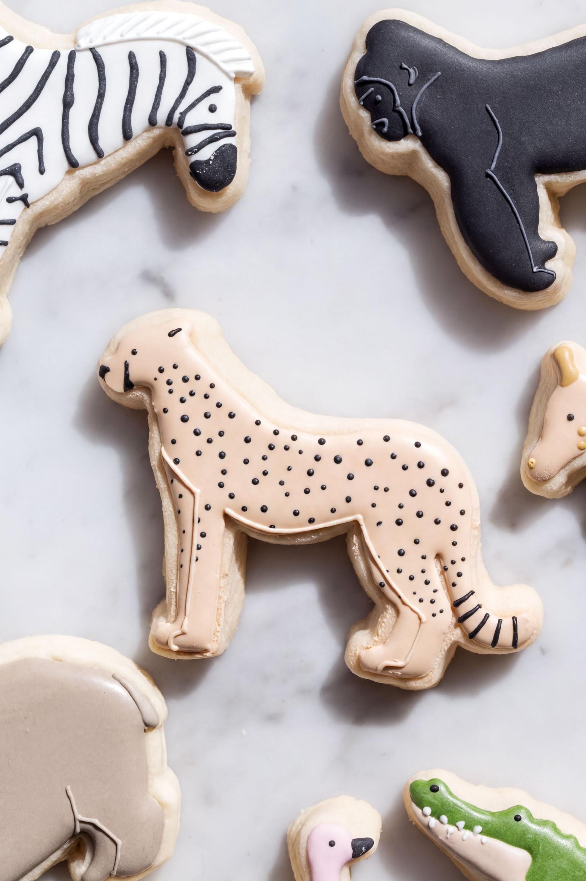 a variety of animal-shaped cookies, including a zebra, a giraffe, a gorilla, and an alligator
