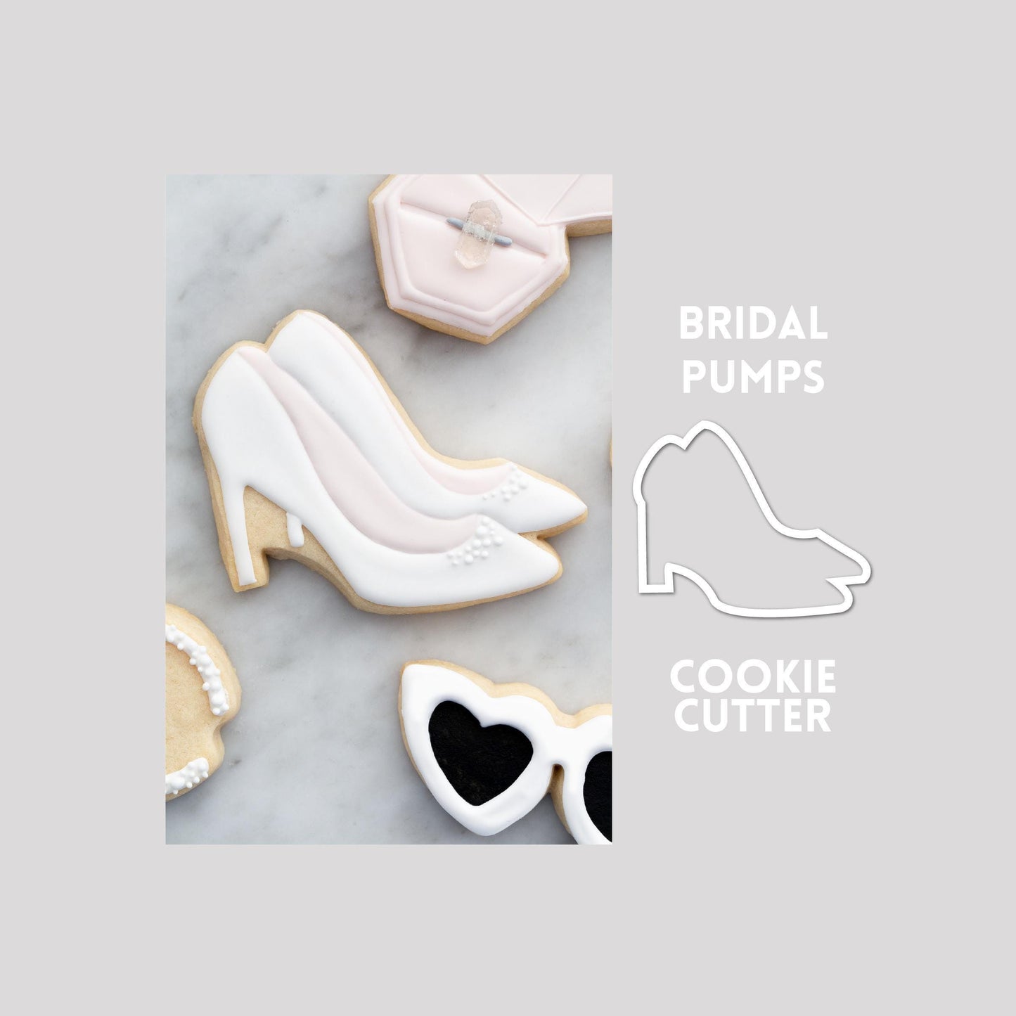 Decorated bridal pumps sugar cookie next to a bridal pumps cookie cutter outline on a gray background.