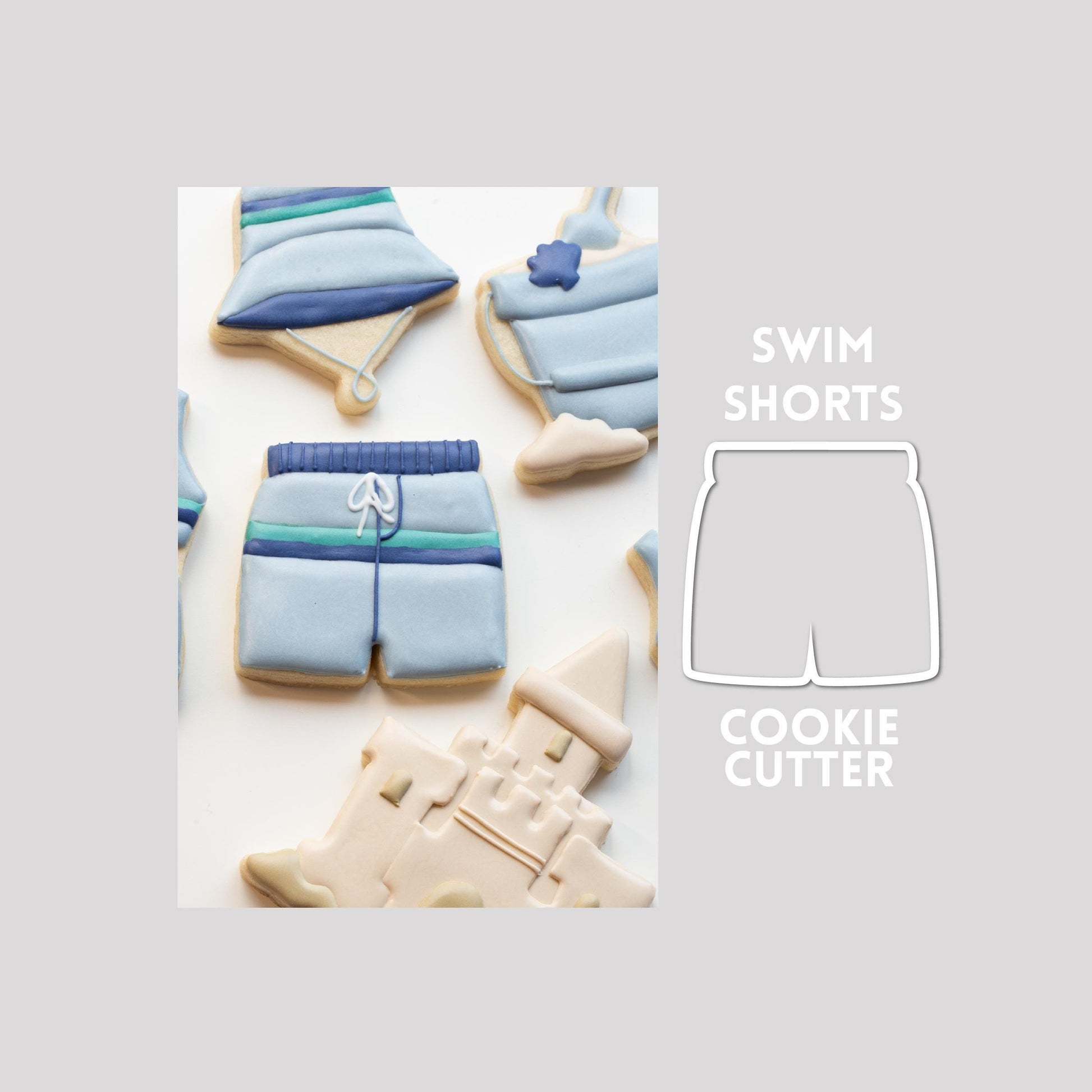 Decorated swim shorts sugar cookie next to a swim shorts cookie cutter outline on a gray background.