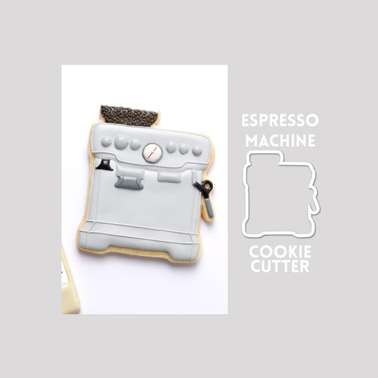 Decorated espresso machine sugar cookie next to a espresso machine cookie cutter outline on a gray background.