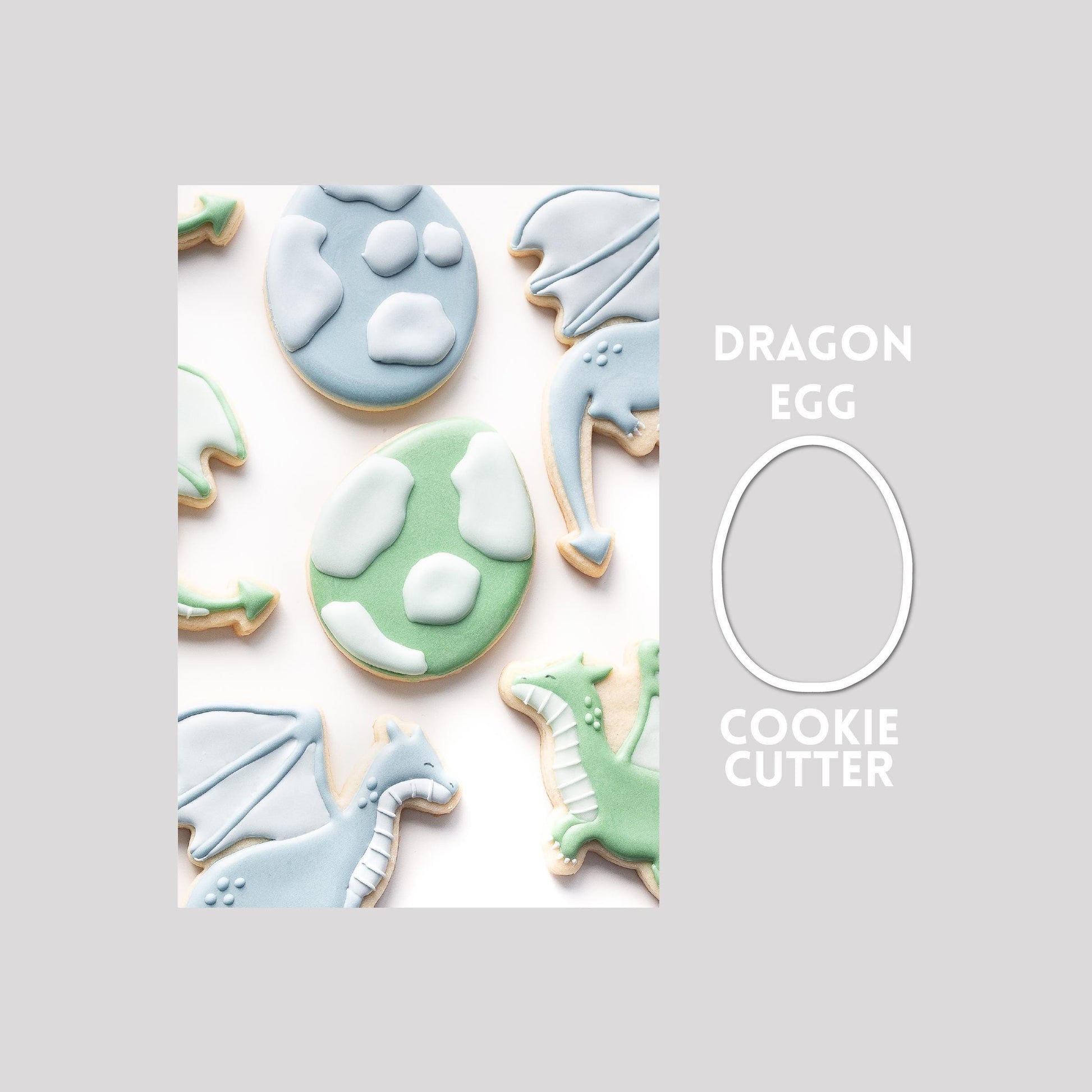 Decorated dragon egg sugar cookie next to a dragon egg cookie cutter outline on a gray background.