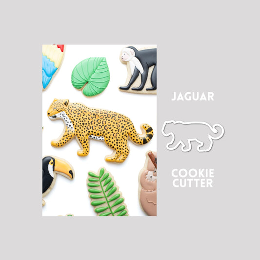 Decorated jaguar sugar cookie next to a jaguar cookie cutter outline on a gray background.