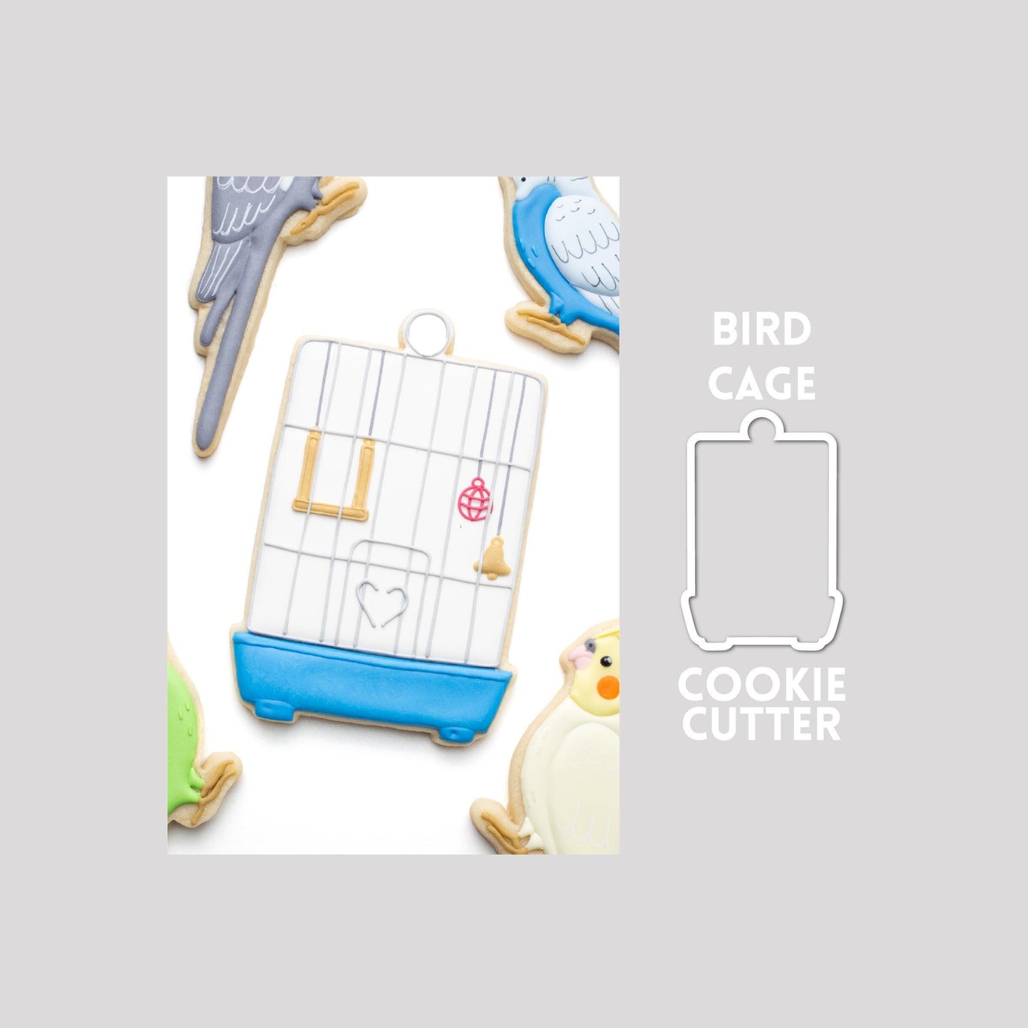 Decorated bird cage sugar cookie next to a bird cage cookie cutter outline on a gray background.
