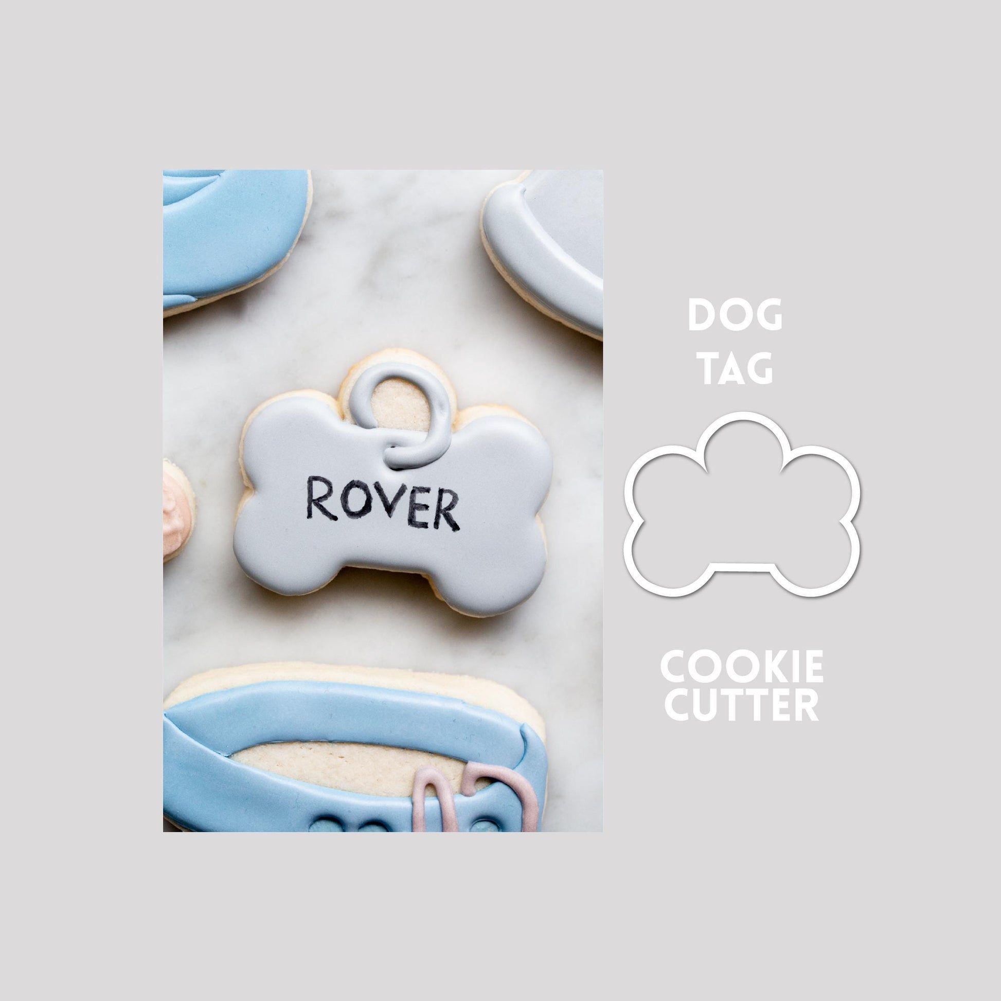 Decorated dog tag sugar cookie next to a dog tag cookie cutter outline on a gray background.