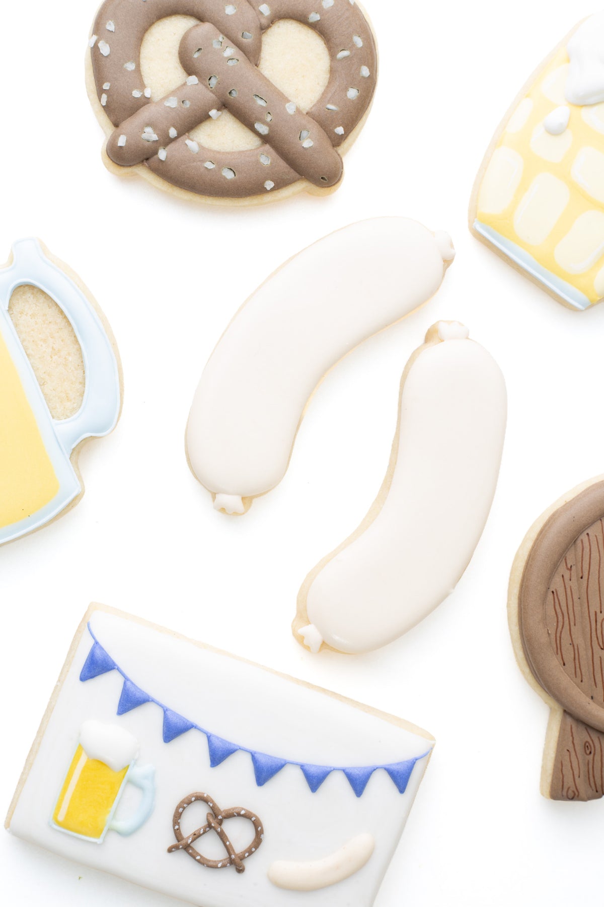 Bratwurst decorated sugar cookies next to a beer mug, pretzel, dimple beer mug, and beer keg decorated sugar cookies.