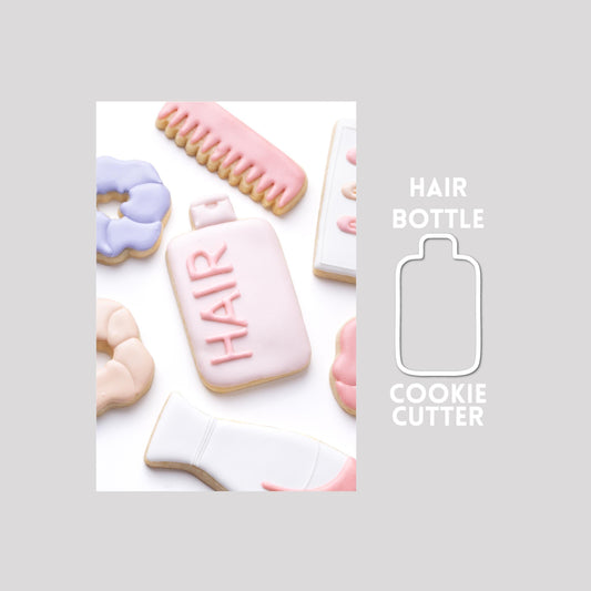 Decorated hair bottle sugar cookie next to a hair bottle cookie cutter outline on a gray background.