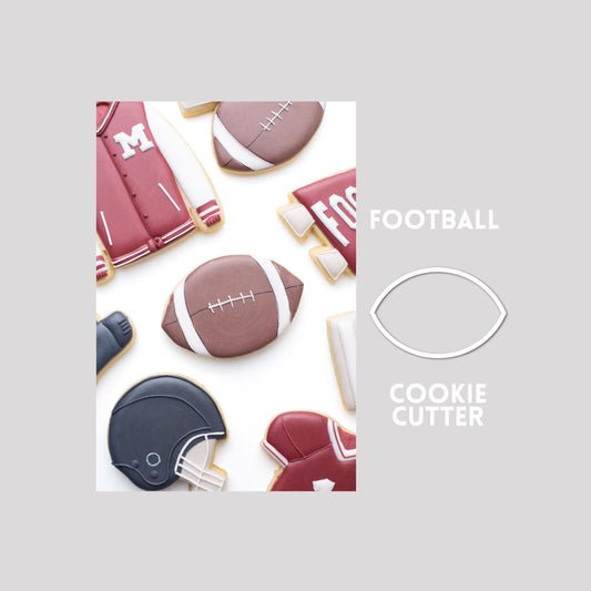 Decorated football sugar cookie next to a football cookie cutter outline on a gray background.