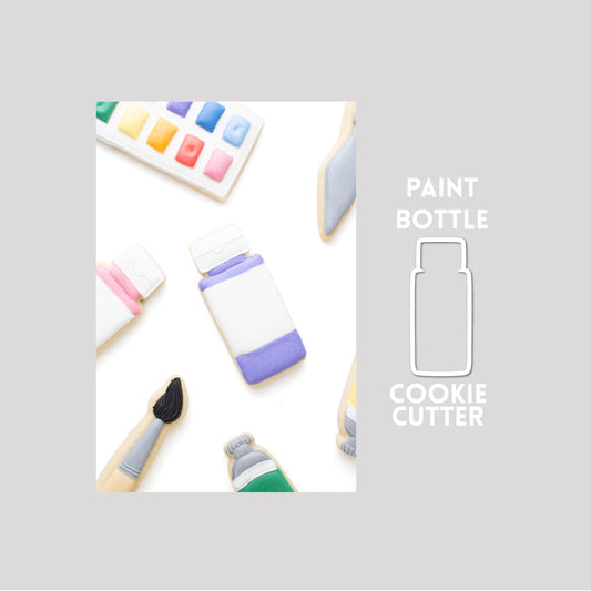 Decorated paint bottle sugar cookie next to a paint bottle cookie cutter outline on a gray background.