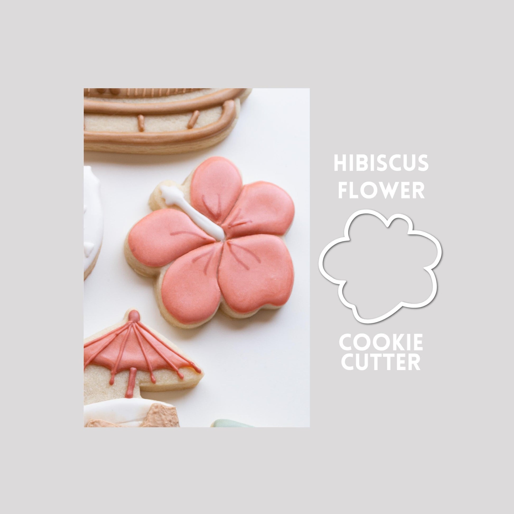 Decorated hibiscus flower sugar cookie next to a hibiscus flower cookie cutter outline on a gray background.