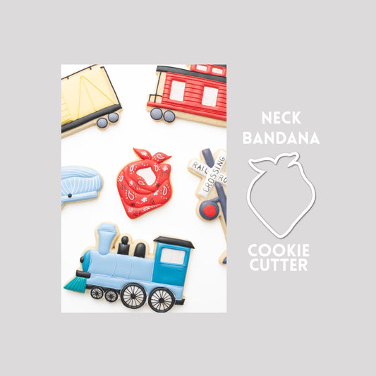 Decorated neck bandana sugar cookie next to a neck bandana cookie cutter outline on a gray background.