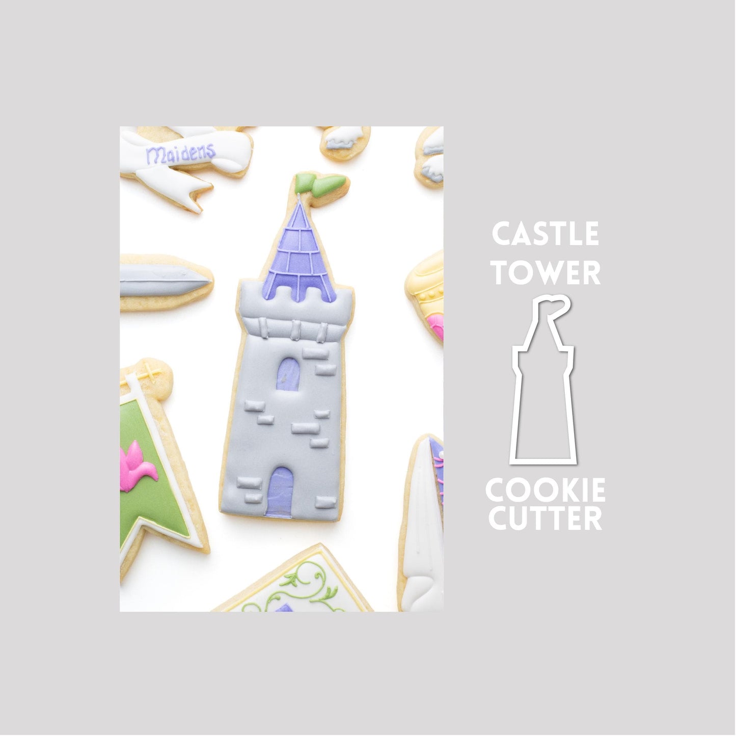 Decorated castle tower sugar cookie  next to a  castle tower cookie cutter outline on a gray background.