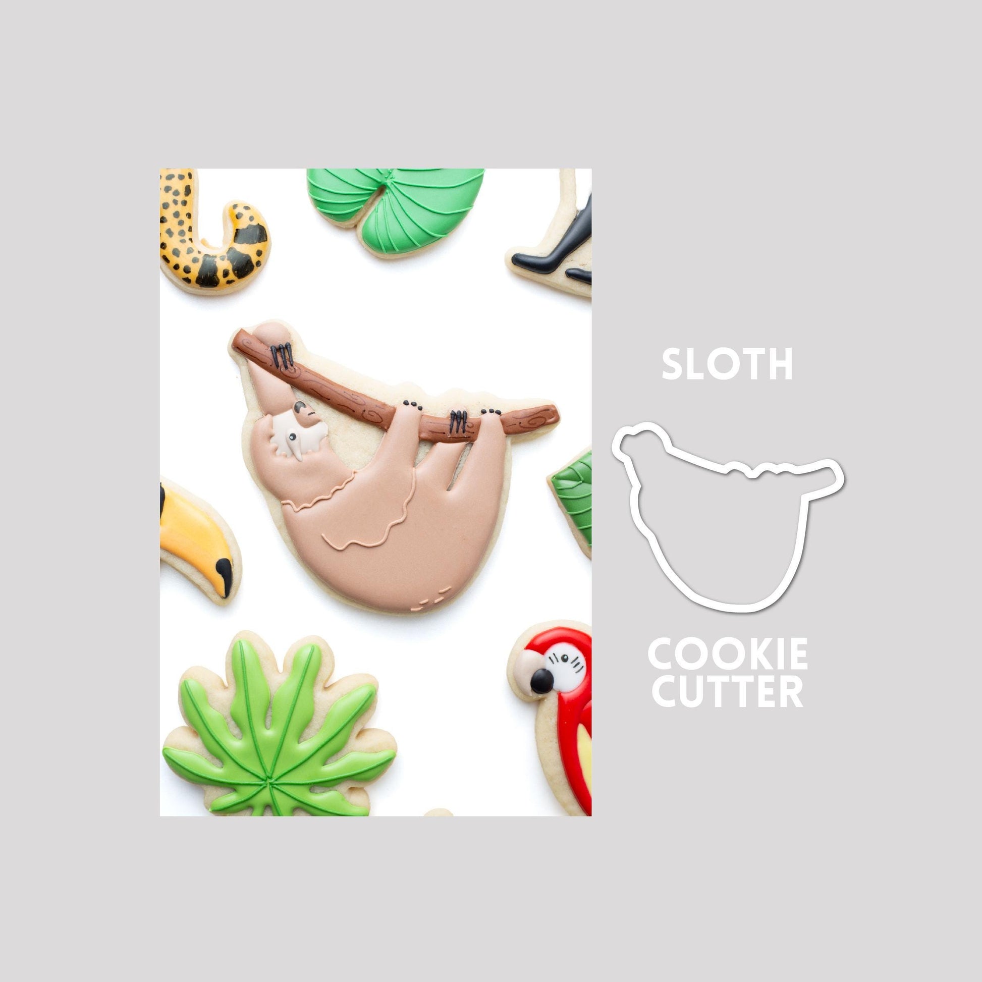 Decorated sloth sugar cookie next to a sloth cookie cutter outline on a gray background.