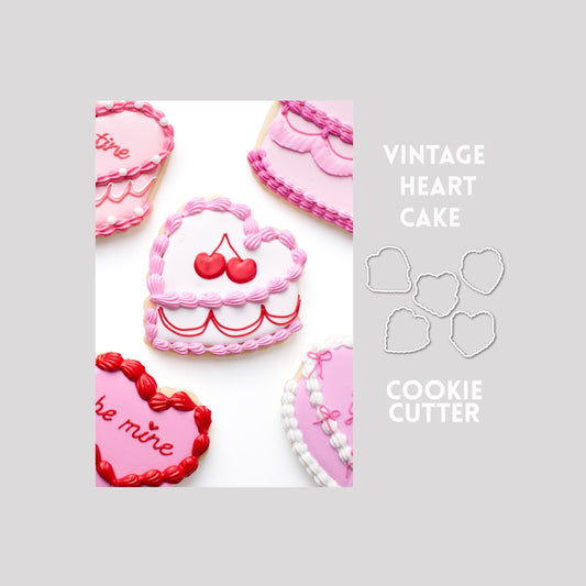 Decorated vintage heart cake sugar cookies next to vintage heart cake cookie cutter outlines on a gray background.