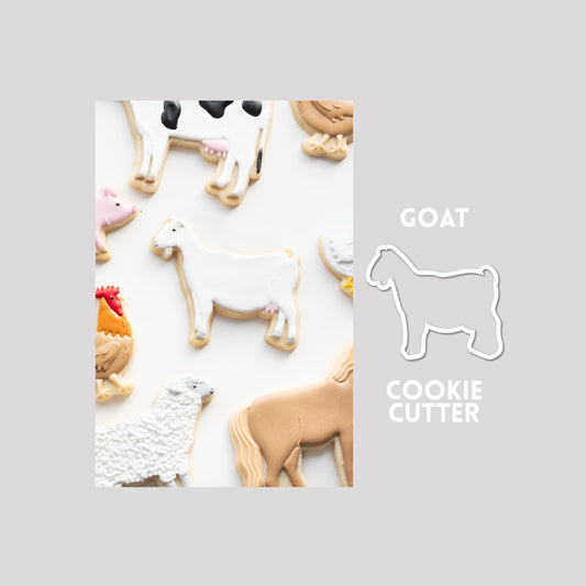 Decorated goat sugar cookie next to a goat cookie cutter outline on a gray background.