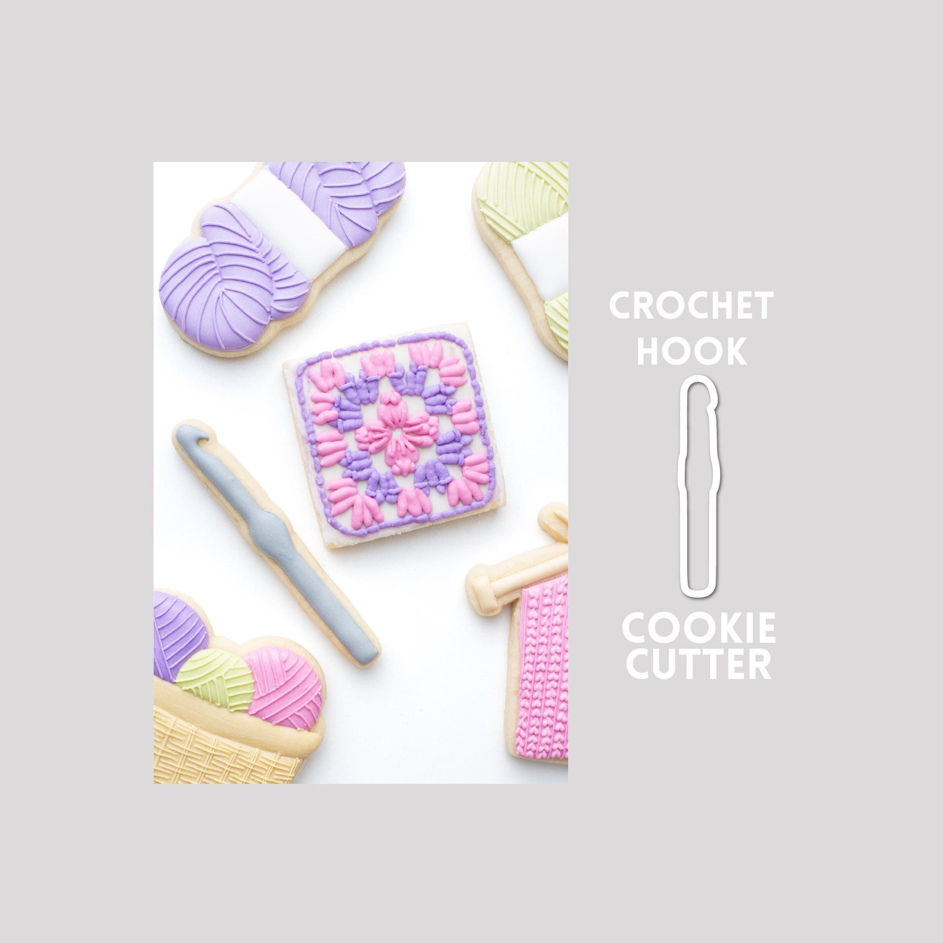 Decorated crochet hook sugar cookie next to a crochet hook cookie cutter outline on a gray background.