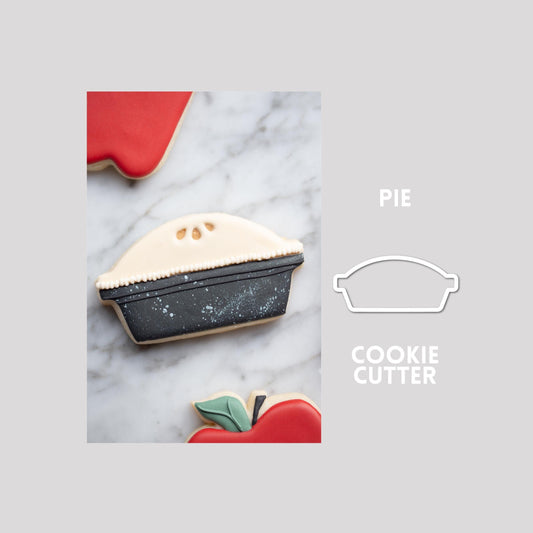 Decorated pie sugar cookie next to a pie cookie cutter outline on a gray background.