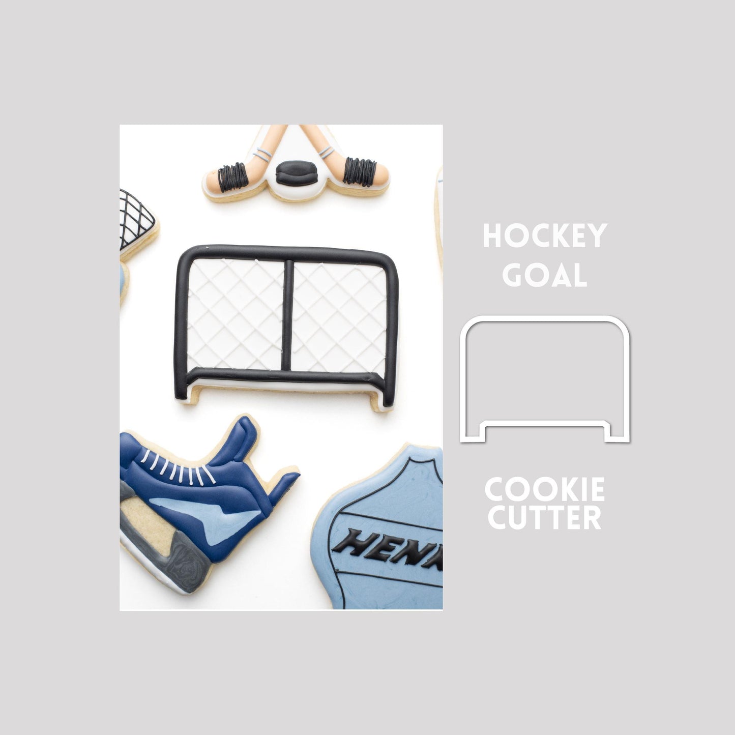 Decorated hockey goal sugar cookie next to a hockey goal cookie cutter outline on a gray background.