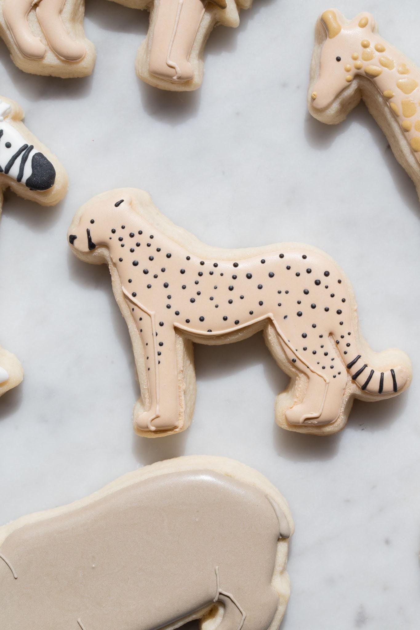 a collection of animal-shaped cookies, including a leopard-shaped cookie, arranged on a white surface.