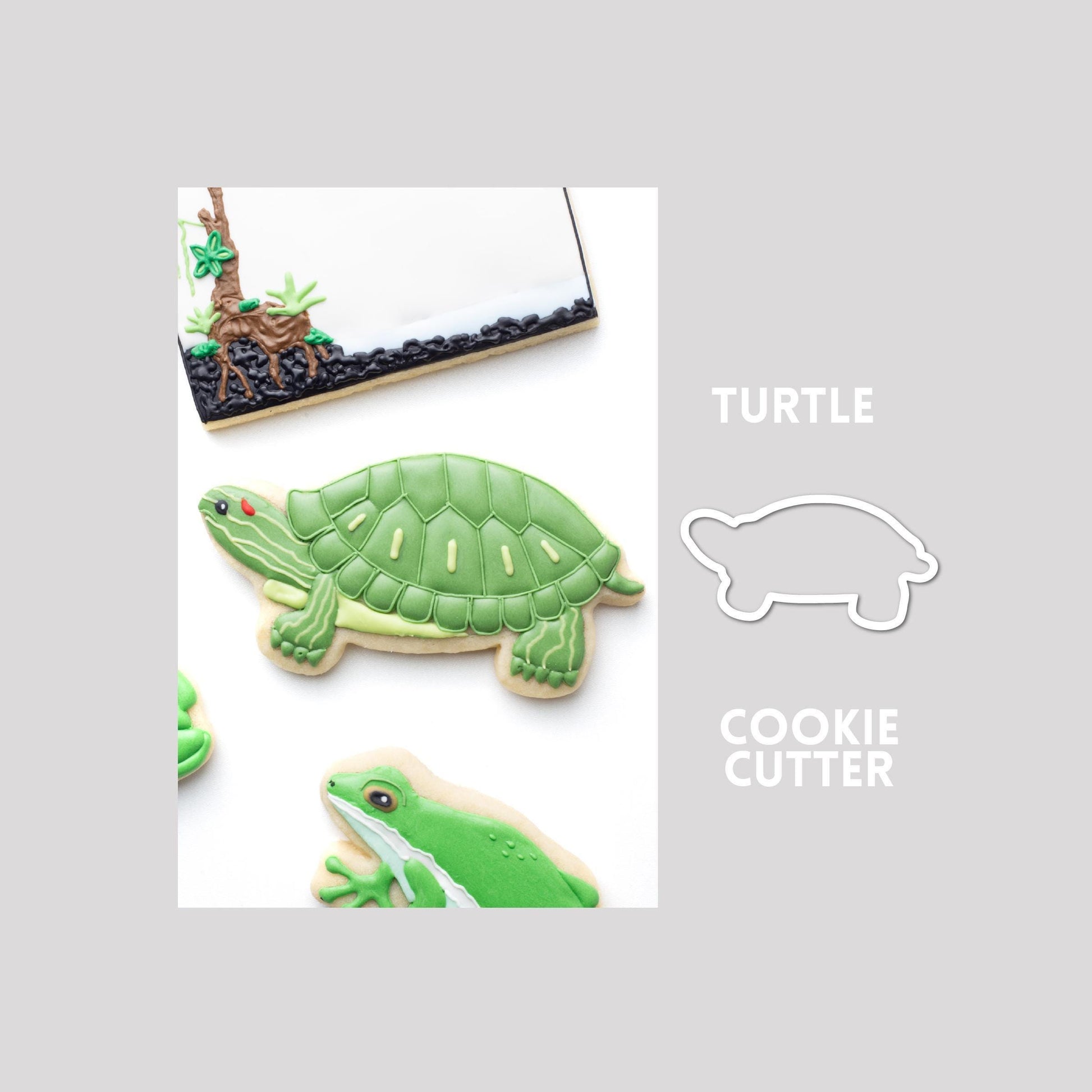 Decorated turtle sugar cookie next to a turtle cookie cutter outline on a gray background.
