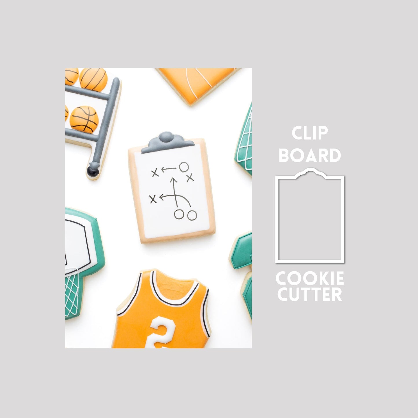 Decorated clipboard sugar cookie next to a clipboard cookie cutter outline on a gray background.