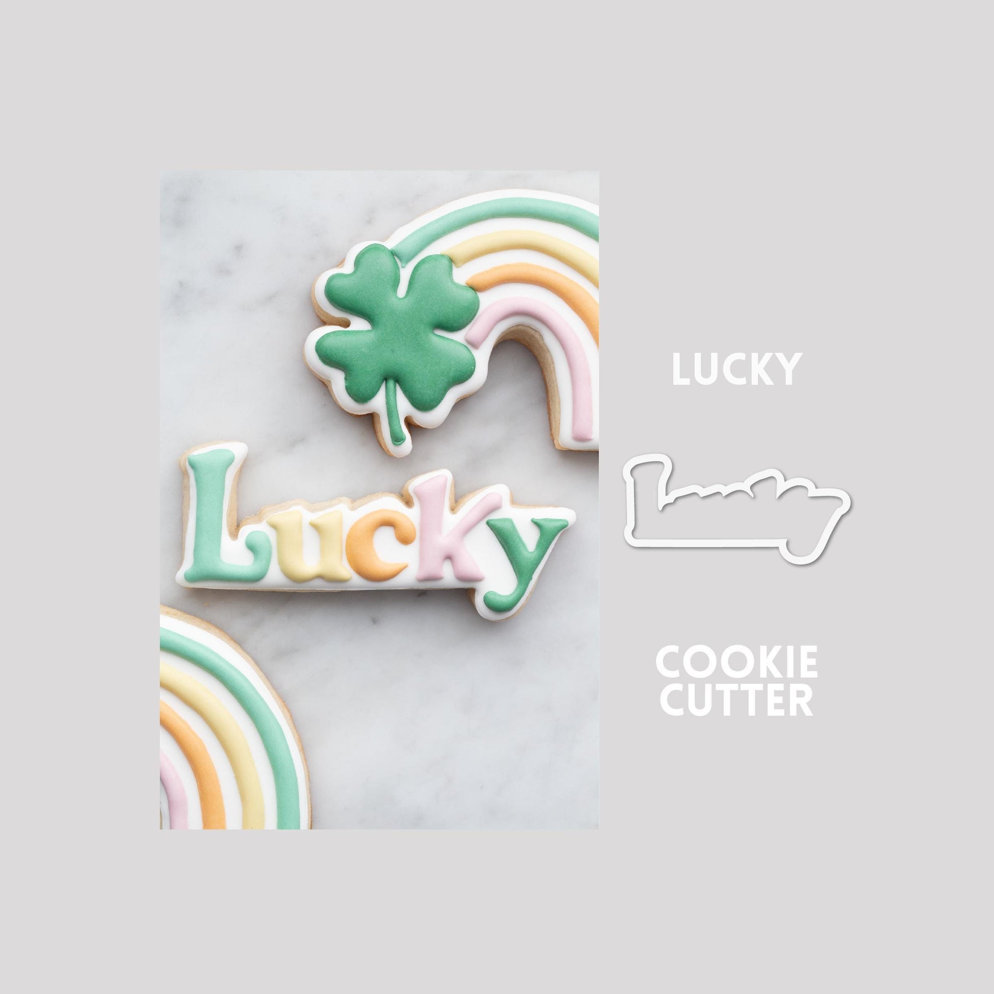 Decorated lucky sugar cookie next to a lucky cookie cutter outline on a gray background.