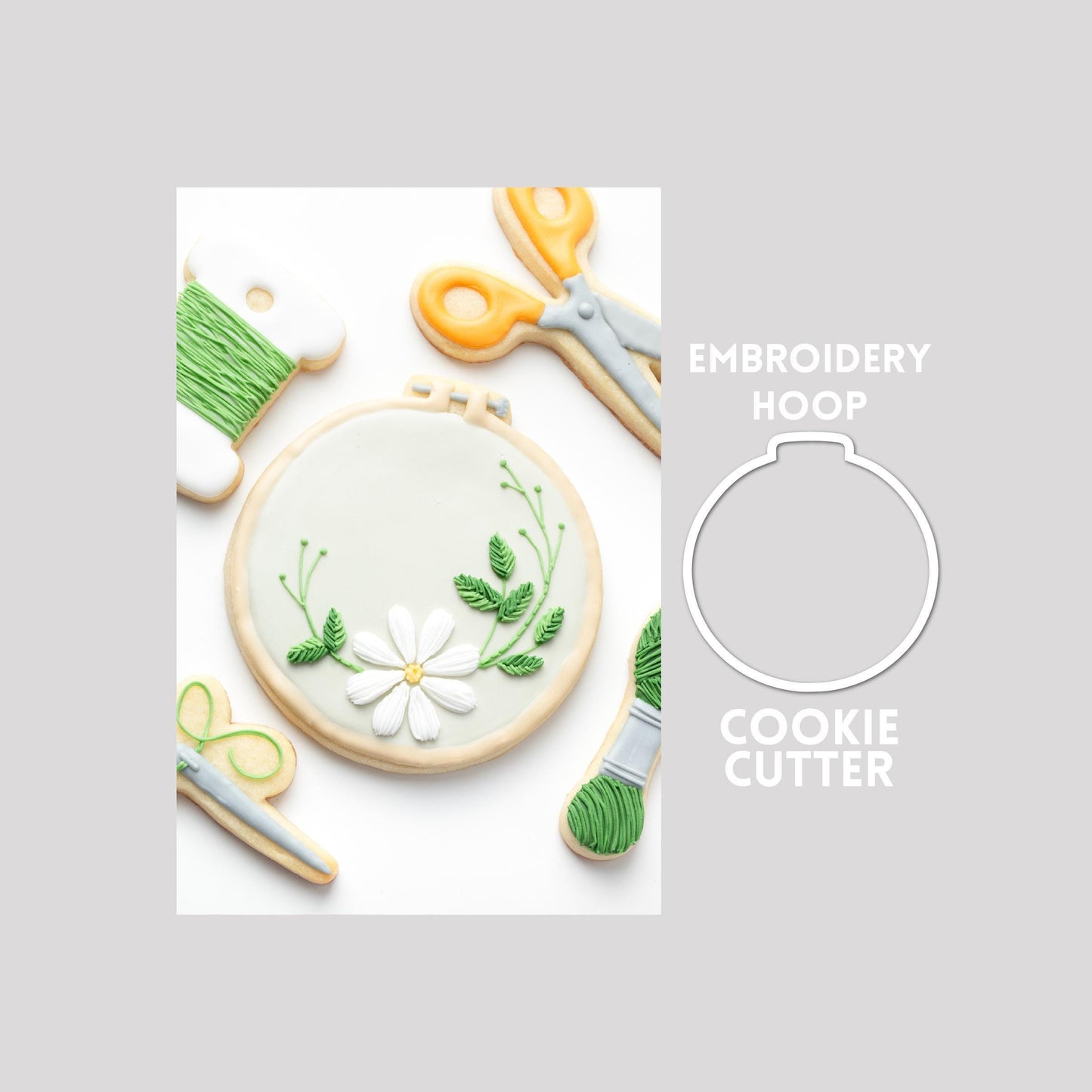 Decorated embroidery hoop sugar cookie next to a embroidery hoop cookie cutter outline on a gray background.