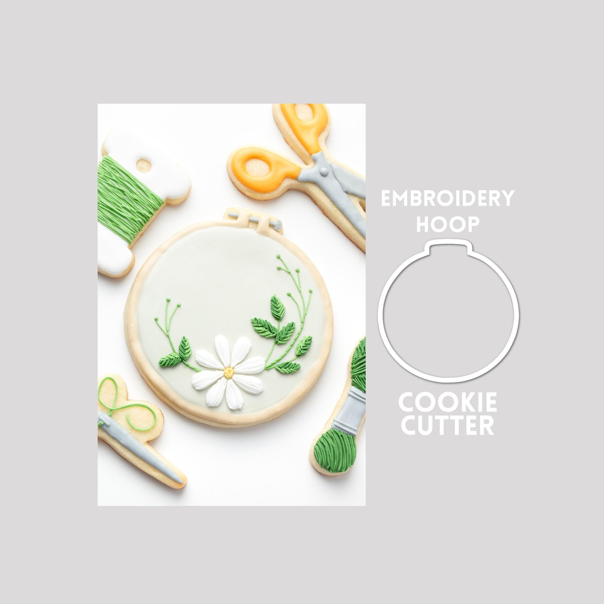 Decorated embroidery hoop sugar cookie next to a embroidery hoop cookie cutter outline on a gray background.