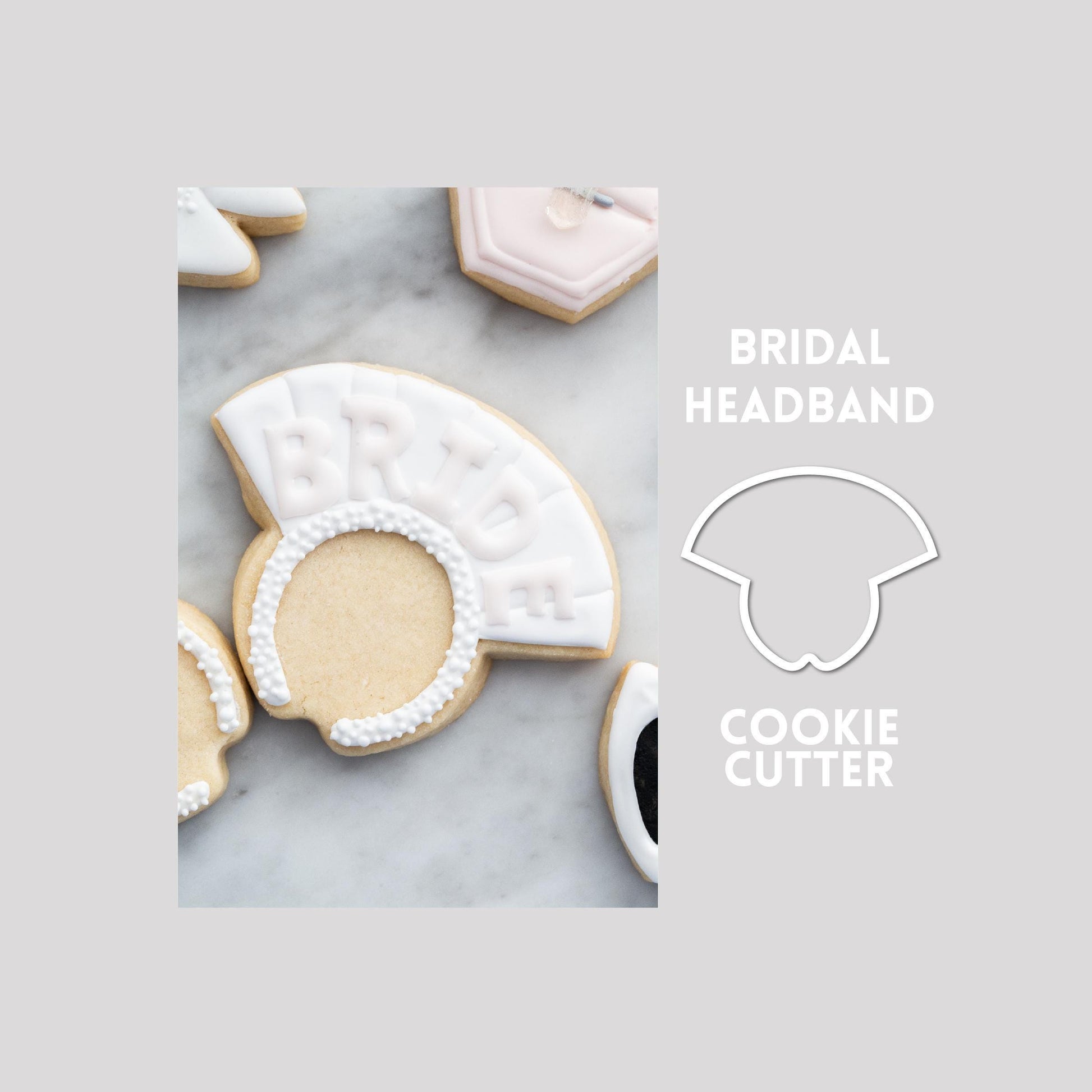 Decorated bridal headband sugar cookie next to a bridal headband cookie cutter outline on a gray background.