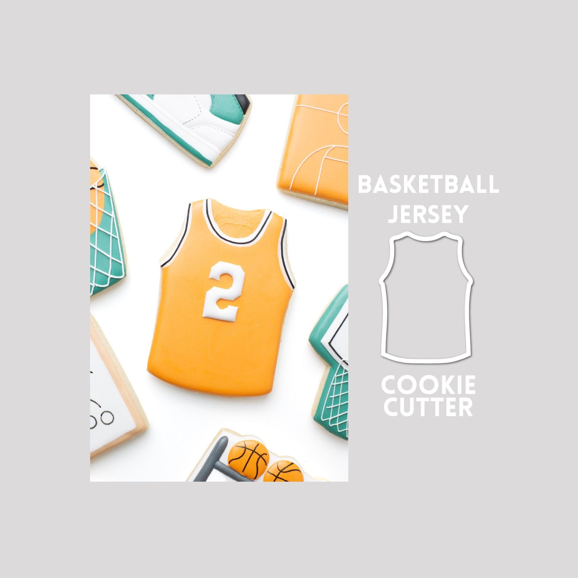 Decorated basketball jersey sugar cookie next to a basketball jersey cookie cutter outline on a gray background.