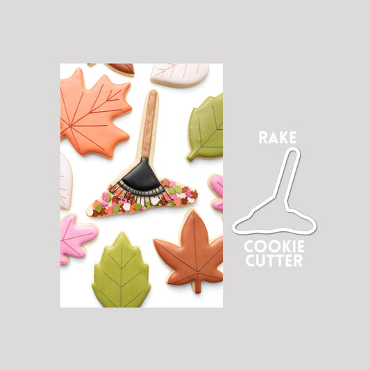Decorated rake sugar cookie next to a rake cookie cutter outline on a gray background.
