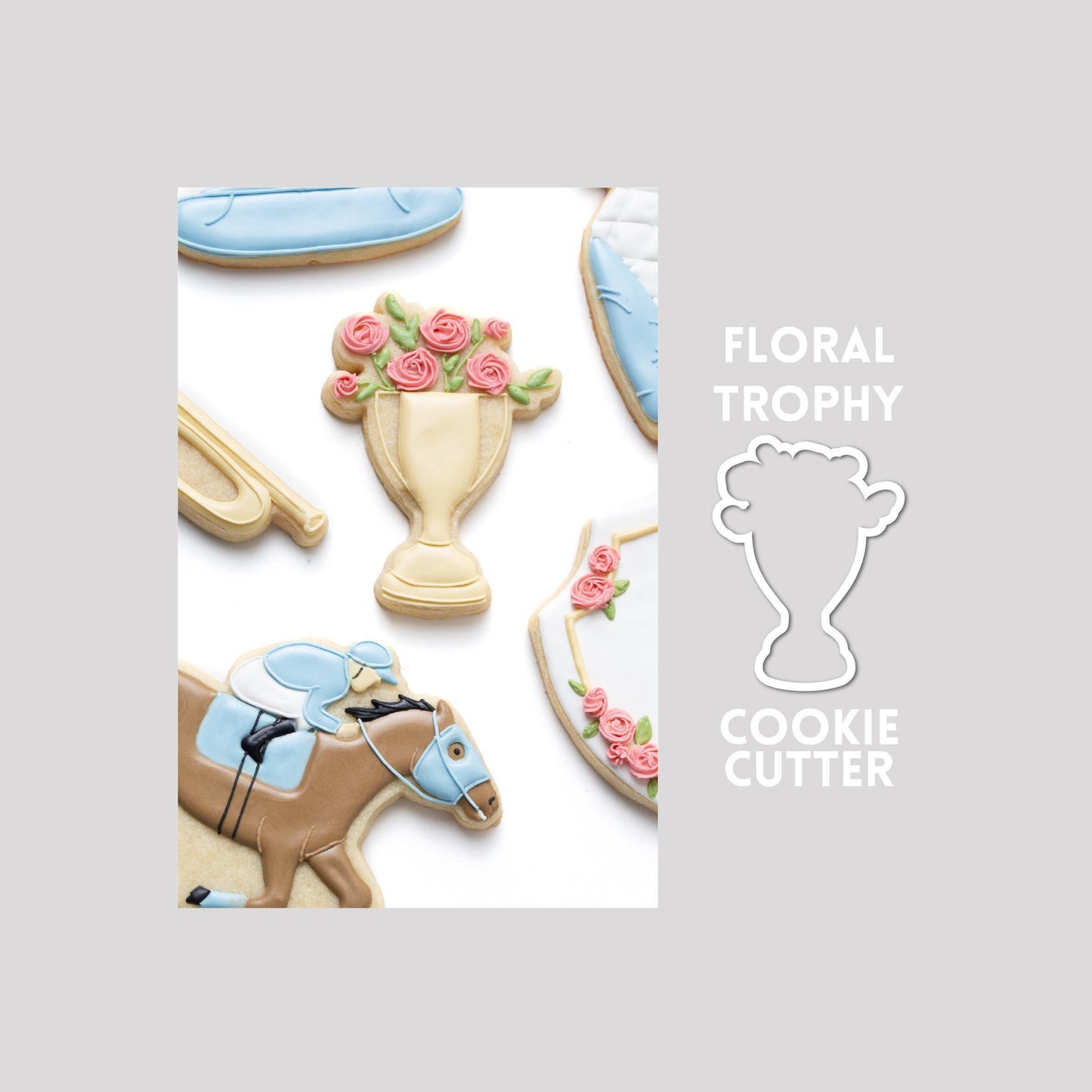 Decorated floral trophy sugar cookie next to a floral trophy cookie cutter outline on a gray background.