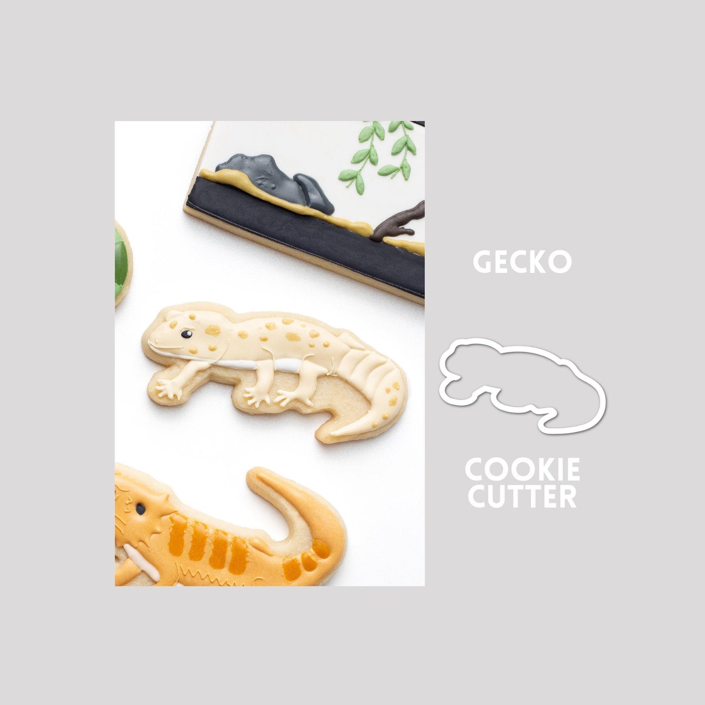 Decorated gecko sugar cookie next to a gecko cookie cutter outline on a gray background.