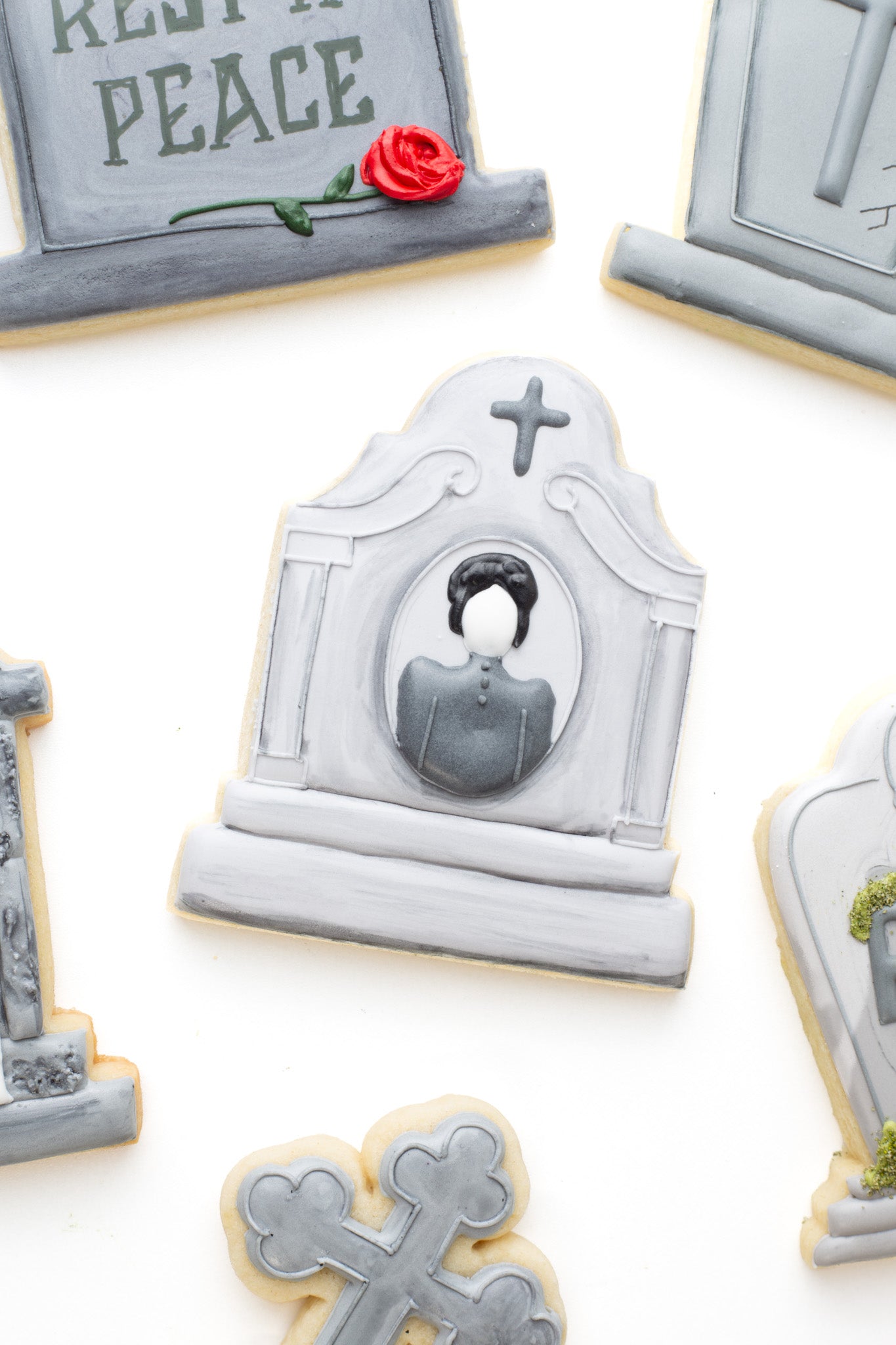 A gravestone with woman and cross decorated sugar cookie next to other gravestones. 