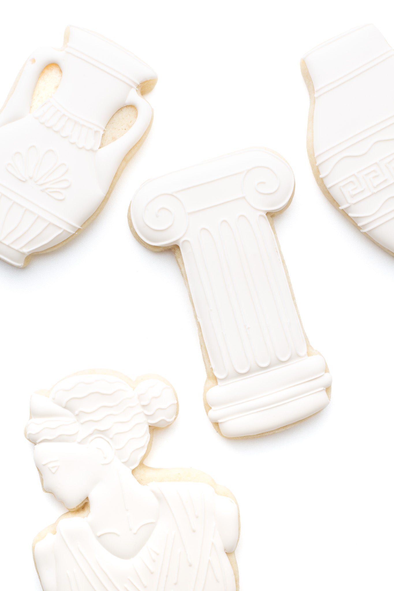 A greek pillar decorated sugar cookie next to greek cases, and greek statue.