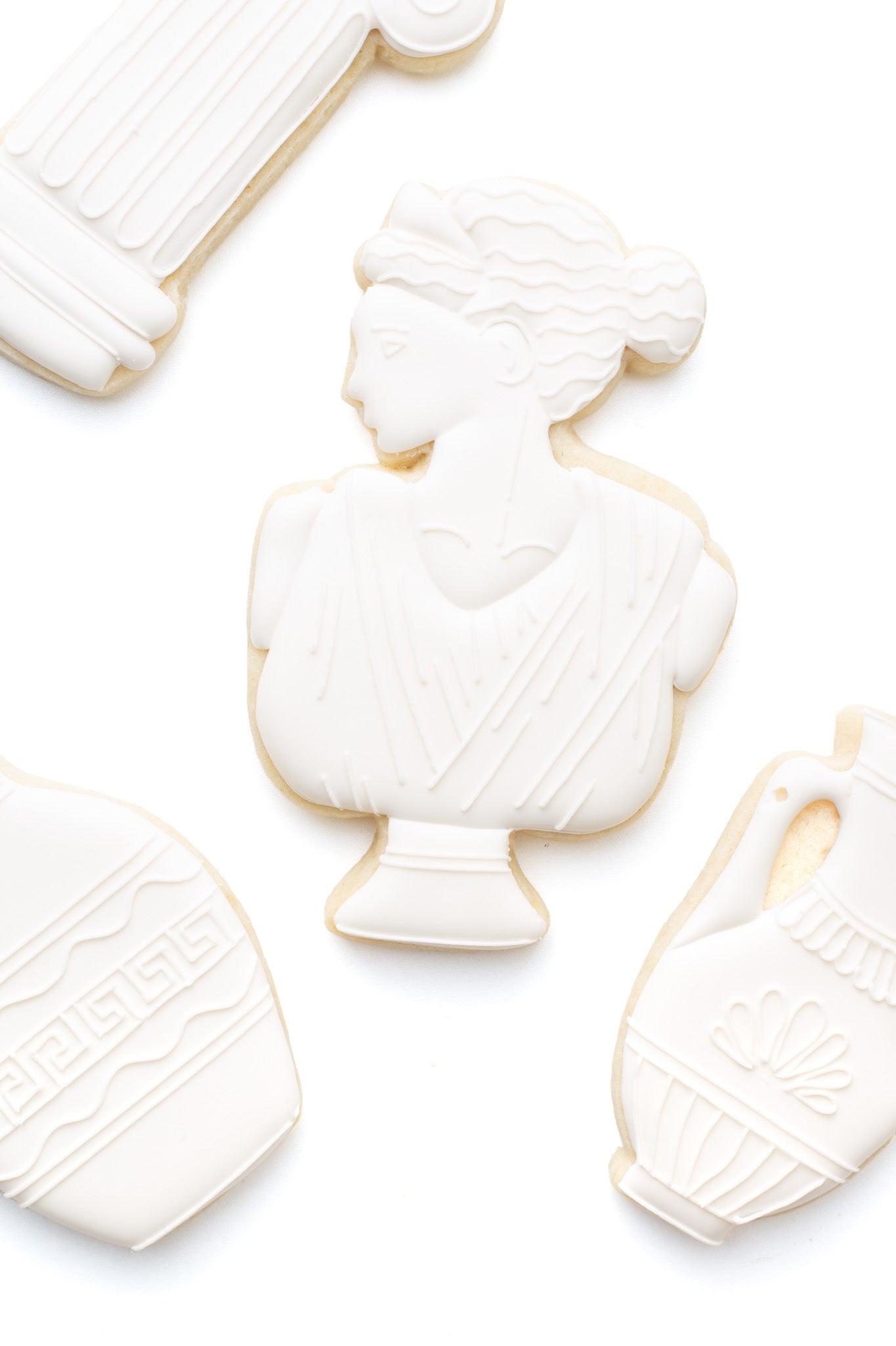 A greek statue decorated sugar cookie next to a greek pillar and greek vases.
