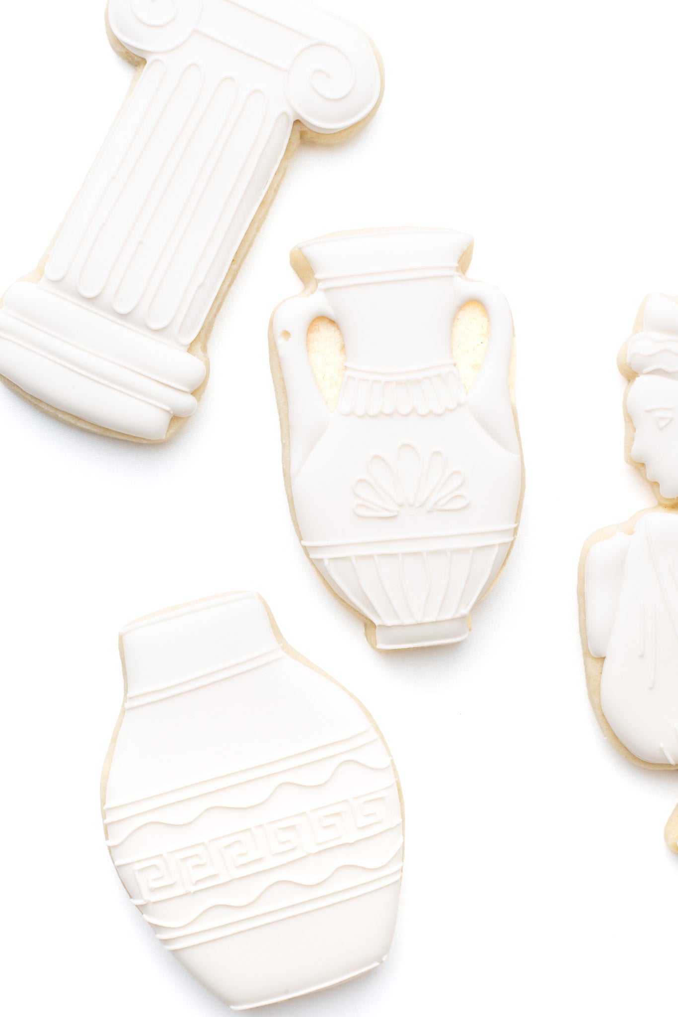 A greek vase decorated sugar cookie next to a greek pillar and greek statue.