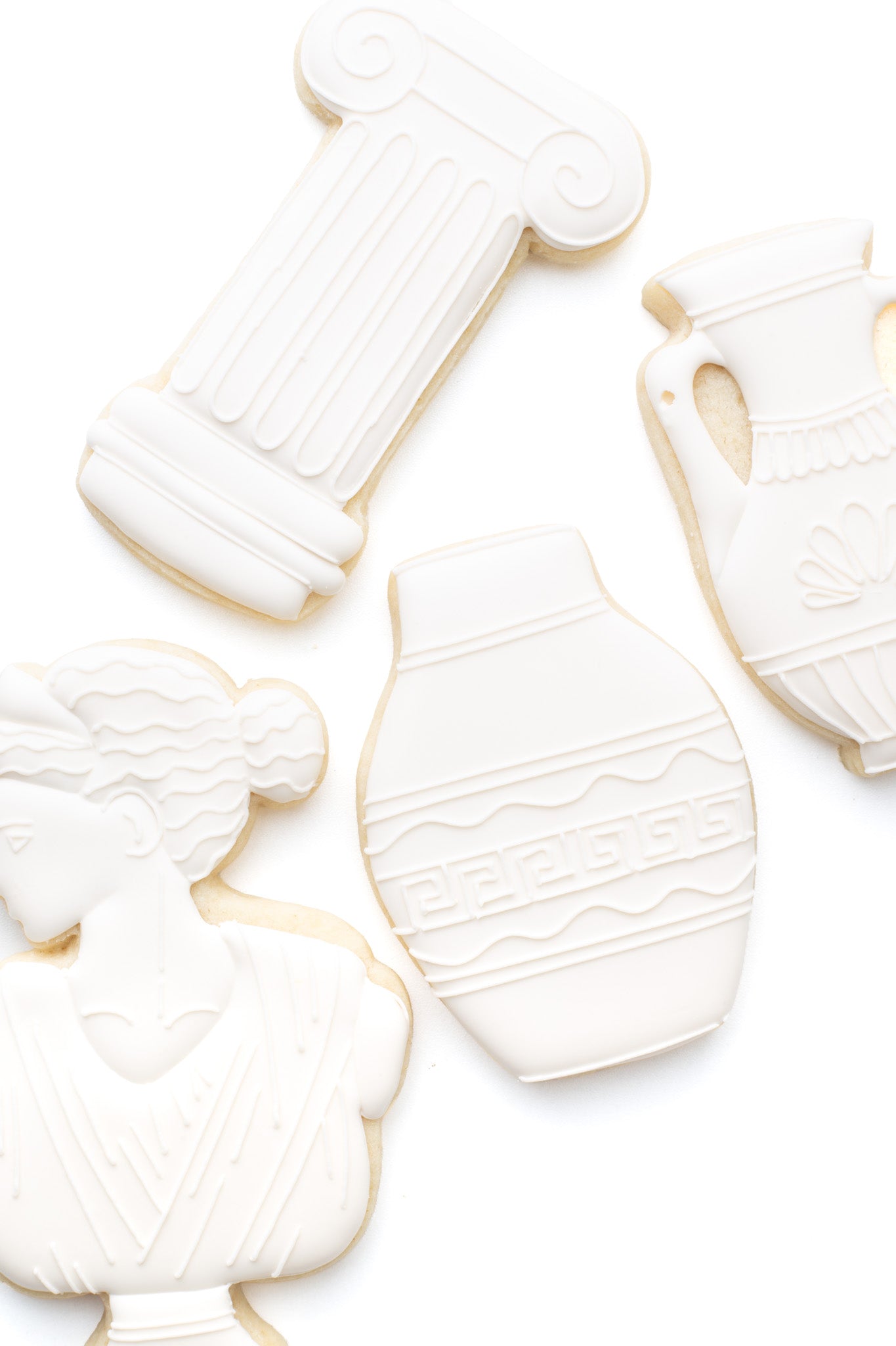 A greek vase decorated sugar cookie next to a greek statue and greek pillar.