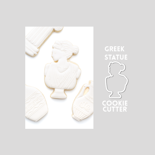 Decorated greek statue sugar cookie next to a greek statue cookie cutter outline on a gray background.