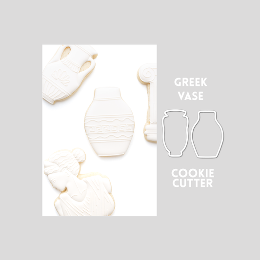 Decorated greek vase sugar cookie next to a greek vase cookie cutter outline on a gray background.
