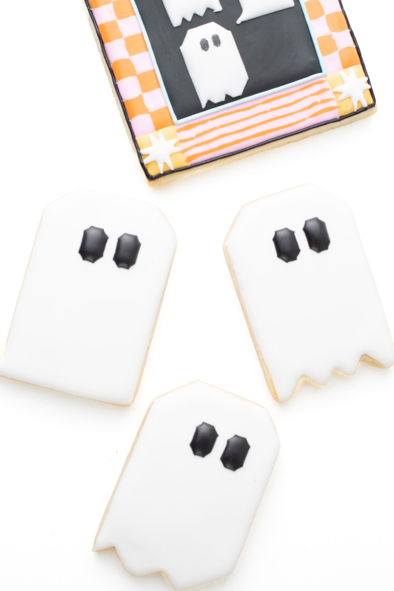 Quilt block ghost shaped decorated sugar cookies next to a quilt with ghosts decorated sugar cookie.