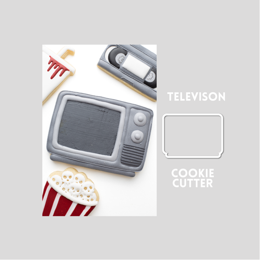 Decorated television sugar cookie next to a television cookie cutter outline on a gray background.